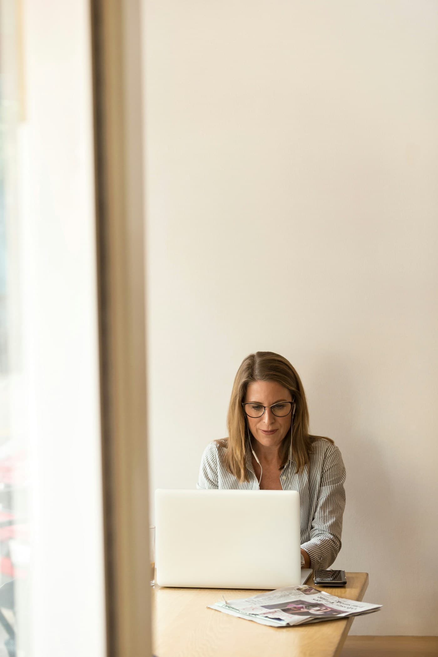 Woman working thoughtfully at a laptop in a bright workspace